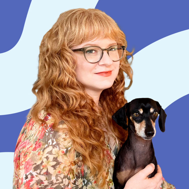 A woman with curly blonde hair and glasses, wearing a floral blouse, holds a black and tan dachshund against a blue and white abstract background.