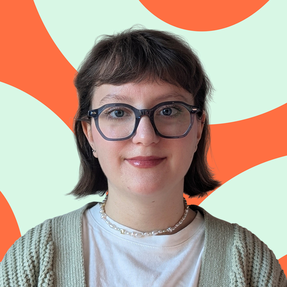 Person with short brown hair and glasses smiling in front of an orange and pale green patterned background.