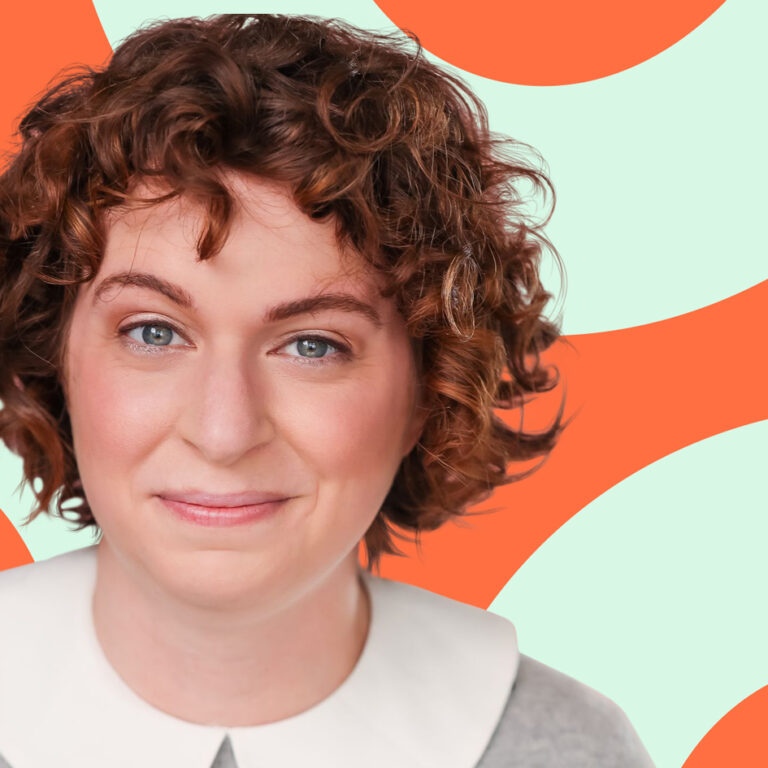 Smiling person with short curly hair and a white collar, in front of an orange and pale green background.